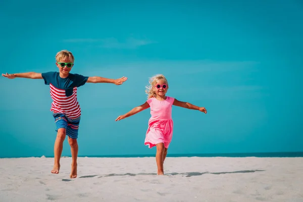 Gelukkig schattig jongen en meisje lopen op het strand — Stockfoto