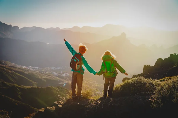 Счастливые мальчик и девочка путешествуют в горах на закате — стоковое фото