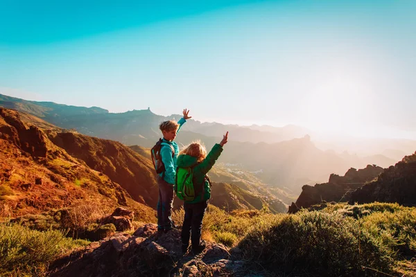 Счастливые мальчик и девочка путешествуют в горах на закате — стоковое фото