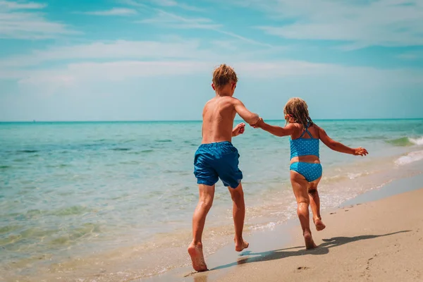 Fată fericită și băiat alerga juca cu valuri pe plajă — Fotografie, imagine de stoc