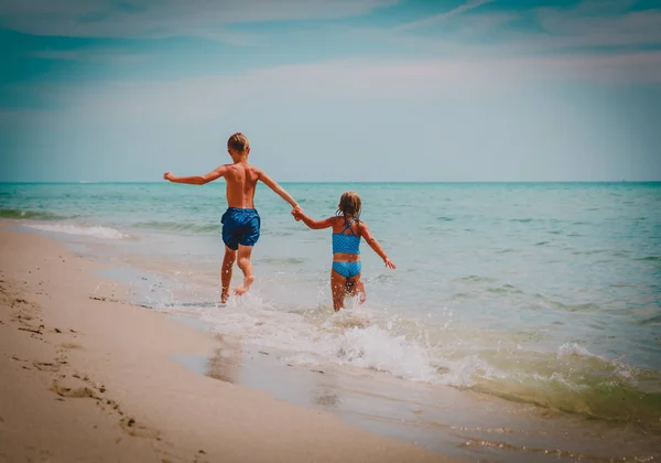 Menina feliz e menino executar jogar com ondas na praia — Fotografia de Stock