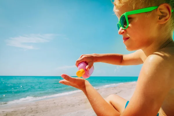 Zon bescherming-Happy Boy met zonnebrandcrème op het strand — Stockfoto