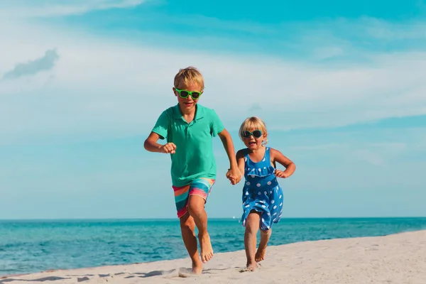 Gelukkig meisje en jongen lopen op het strand, kinderen spelen op vakantie — Stockfoto