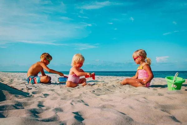 Miúdos e raparigas brincam com areia na praia. — Fotografia de Stock