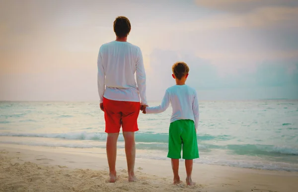father and son holding hands at beach