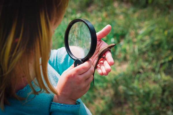 дети учатся - ребенок исследует ящерицу с лупой
