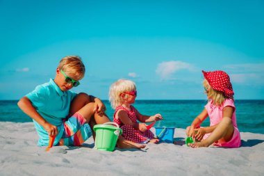 Çocuklar yaz plajında kumla oynarlar.