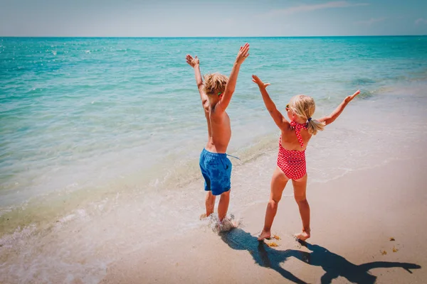 Счастливые мальчик и девочка играют на пляже — стоковое фото