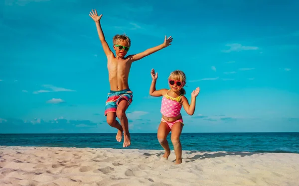 Kleine jongen en meisje dans op strand, kinderen genieten van vakantie op zee — Stockfoto