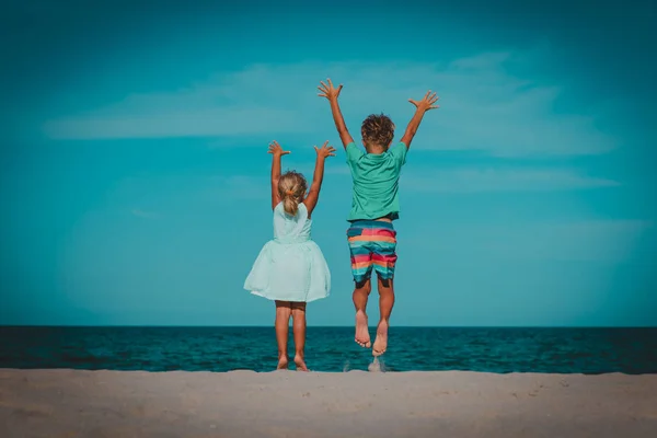 Šťastný chlapec a dívka hrají na pláži, děti skáčou a baví se — Stock fotografie