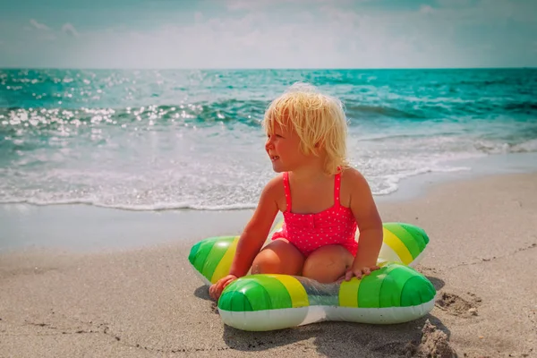 Niedliches kleines Mädchen mit schwimmendem Spielzeugring am Strand — Stockfoto