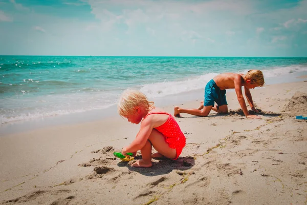 Littlegirl y chico jugar con arena en la playa — Foto de Stock