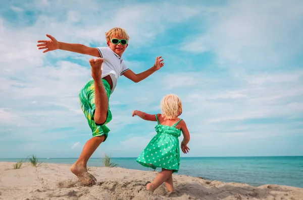 Güzel erkek ve kız sahilde dans ediyor, çocuklar denizde tatilin tadını çıkarıyor. — Stok fotoğraf