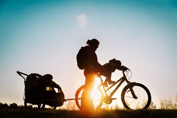 Мати і маленькі дочки катаються на велосипеді на заході сонця — стокове фото