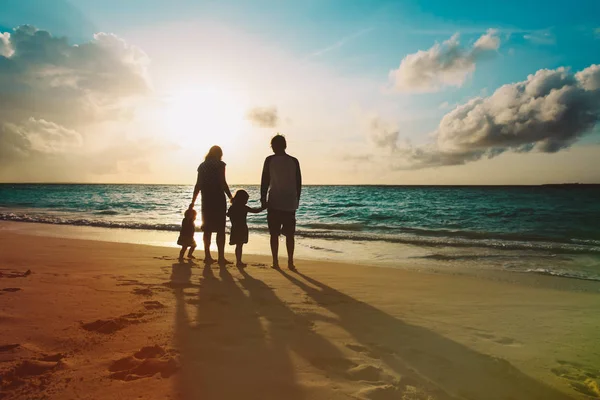 Glückliche Familie mit Kindern spazieren am Strand bei Sonnenuntergang — Stockfoto