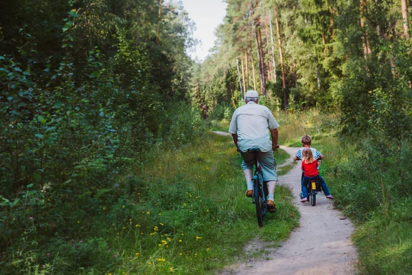 与孙子孙女一起在大自然中骑自行车的高年级生 — 图库照片