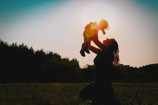 Mãe e pequeno bebê brincam no pôr do sol natureza — Fotografia de Stock