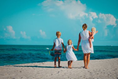 Anne ile oğlu ve kızı plajda yürüyüş