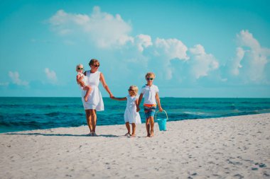 Anne ile oğlu ve kızı plajda yürüyüş