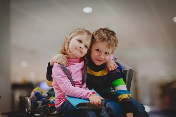 Liten pojke och flicka vänta i flygplats, sitta på bagage, familj resor — Stockfoto