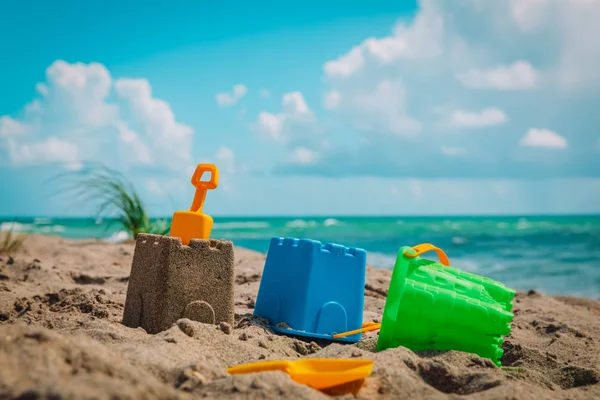 Zandkasteel en speelgoed op tropisch strandvakantie — Stockfoto