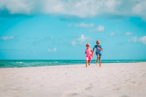 Feliz lindo chico y chica ejecutar jugar en la playa —  Fotos de Stock