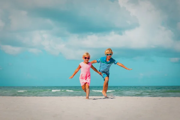 Šťastný chlapec a děvče hrají na pláži. — Stock fotografie