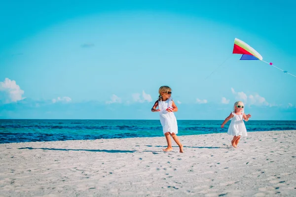 Kleine meisjes vliegen een vlieger op tropisch strand — Stockfoto