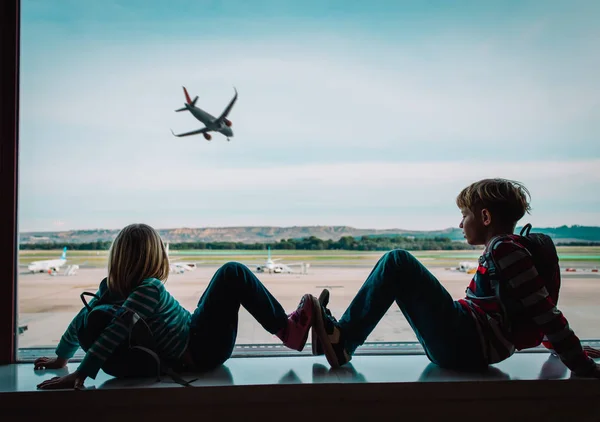 Дети смотрят на самолет в аэропорту, семейные поездки — стоковое фото