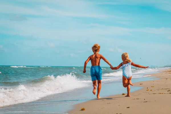 Šťastný chlapec a dívka běží na pláži — Stock fotografie