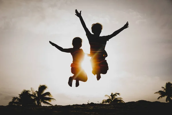 Dzieci bawią się, chłopiec i dziewczynka skok na plaży Sunset — Zdjęcie stockowe