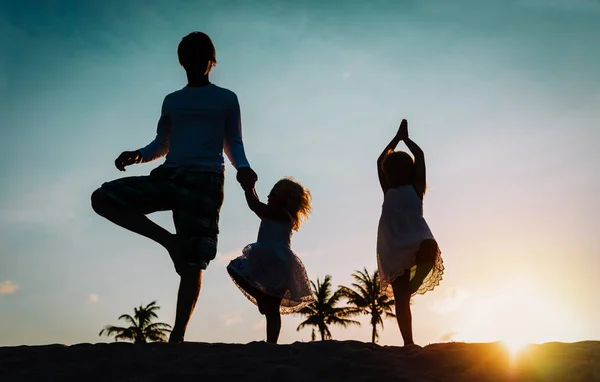 Vader met kinderen silhouetten oefening bij Sunset Beach — Stockfoto