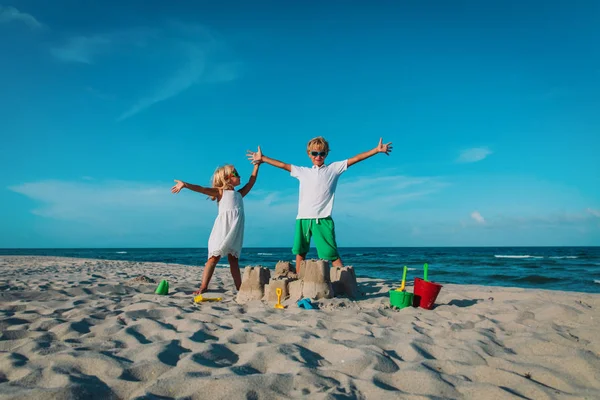 Gelukkig jongen en meisje spelen met zand op het strand — Stockfoto