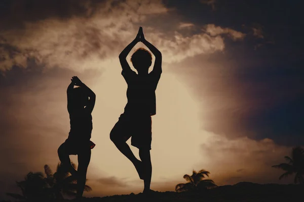 Crianças exercício na praia do por do sol, menino e menina fazendo ioga — Fotografia de Stock