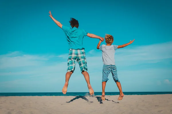 Apa és fia érezd jól magad ugrás trópusi tengerparton — Stock Fotó