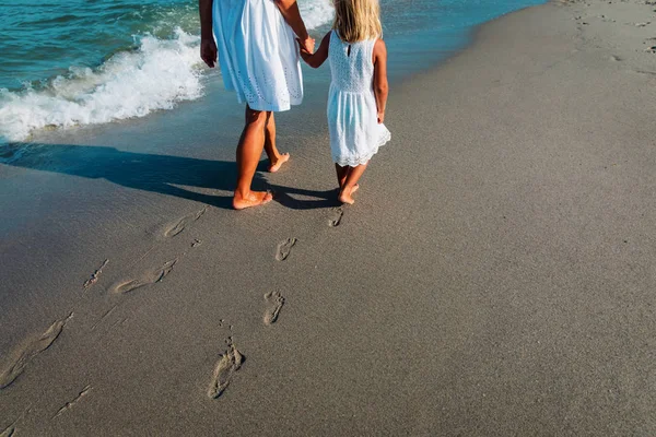 Mère et fille marchant sur la plage laissant une empreinte dans le sable — Photo