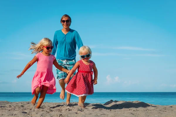 Gelukkige familie-vader met schattige kleine dochters spelen op het strand — Stockfoto