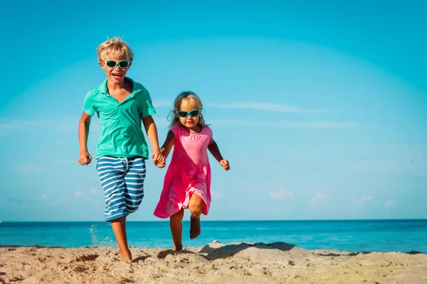 Leuke gelukkige jongen en meisje rennen op het strand — Stockfoto