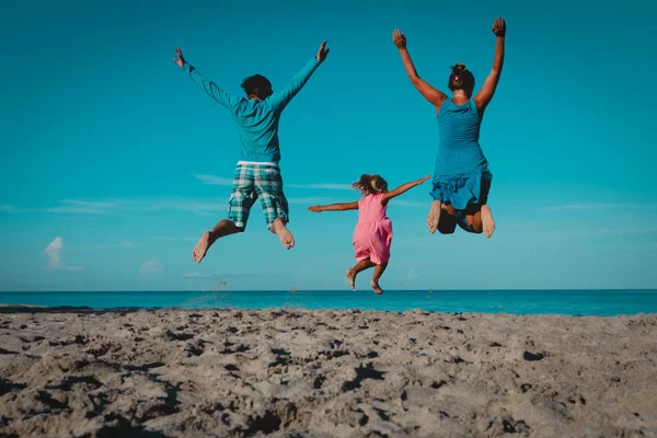 Gelukkige familie-moeder, vader en kleine dochter-springen op het strand — Stockfoto