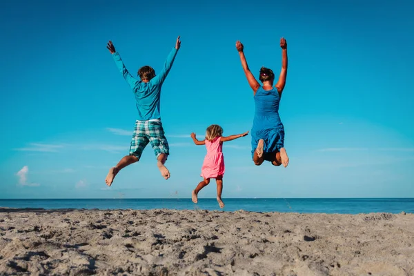 Gelukkige familie-moeder, vader en kleine dochter-springen op het strand — Stockfoto