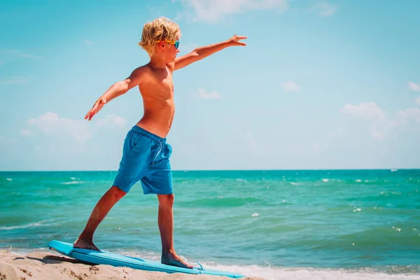 Jonge jongen leren surfen op zee strand — Stockfoto