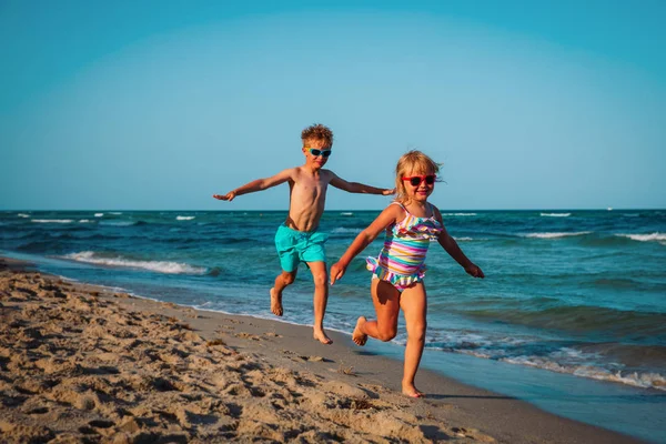 Schattig gelukkig meisje en jongen rennen op het strand — Stockfoto