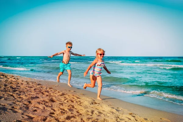 Schattig gelukkig meisje en jongen rennen op het strand — Stockfoto