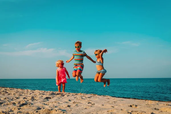 Ευτυχισμένα παιδιά άλμα στην παραλία, αγόρι και κορίτσια που διασκεδάζουν στη θάλασσα — Φωτογραφία Αρχείου