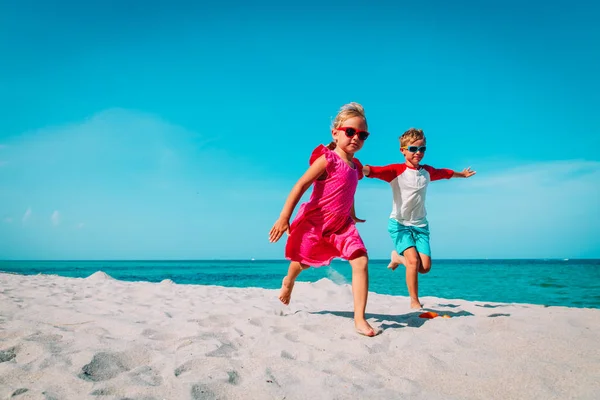 Gelukkig jongen en meisje run spelen op het strand — Stockfoto