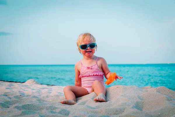 Mignonne petite fille heureuse jouer avec le sable sur la plage — Photo