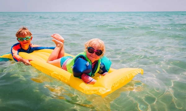 Ευτυχισμένο αγόρι και κορίτσι κολυμπούν σε φουσκωτό στρώμα στη θάλασσα — Φωτογραφία Αρχείου