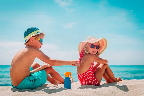 Защита от солнца, милая девушка и мальчик с кремом для загара на пляже — стоковое фото