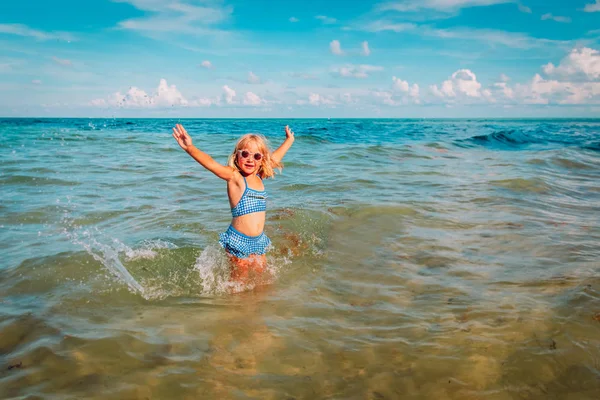 Милая счастливая девушка играть с водой и веселиться на пляже — стоковое фото