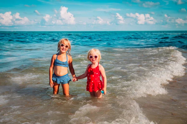 Gelukkig schattige kleine meisjes spelen met water op het strand — Stockfoto